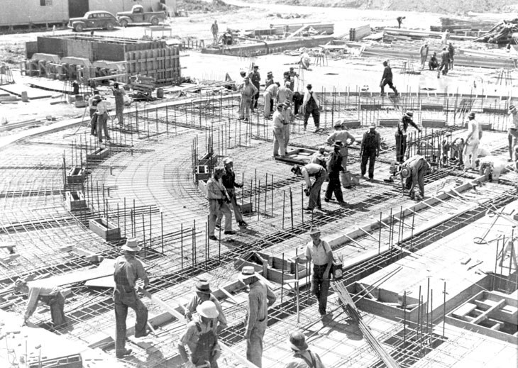 Μία Άλφα οβάλ διάταξη καλουτρονίων (racetrack) υπό κατασκευή στο Y-12, Όουκ Ριτζ, το 1943: εργάτες πάνω σε ράβδους οπλισμού και σκυρόδεμα.